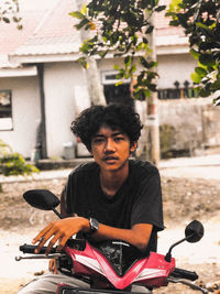 Portrait of young man sitting on bicycle in city