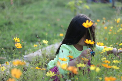 Girl with fidget spinner by flowers on field