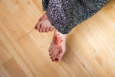 Low section of bride with henna tattoo on hardwood floor
