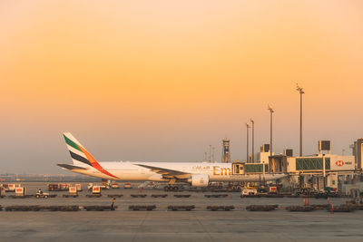 Airplane on airport runway against sky during sunset