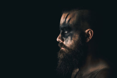 Close-up of man looking away against black background