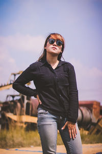 Portrait of young woman wearing sunglasses while standing on field