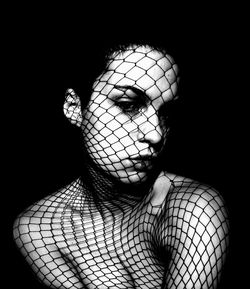 Close-up portrait of young woman over black background