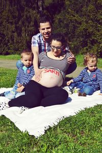 Full length of father and daughter sitting on grass