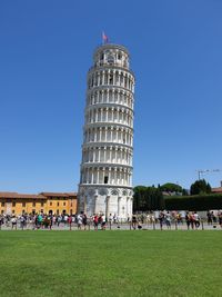 Group of people in front of building against clear blue sky