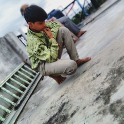 High angle view of boy sitting on wood