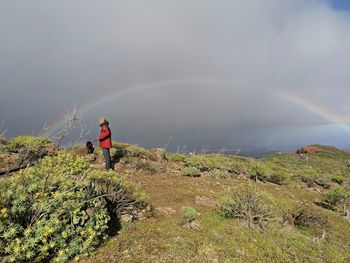 Rear view of man standing against rainbow in sky