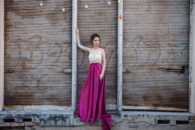 Portrait of woman standing against pink wall