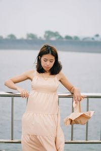 Woman standing by railing against sea