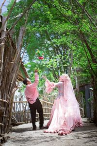 Rear view of married couple throwing flower while standing outdoors