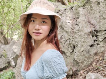 Portrait of young woman standing against rock