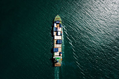 Aerial view container ship sailing on the green sea full speed container for logistics,