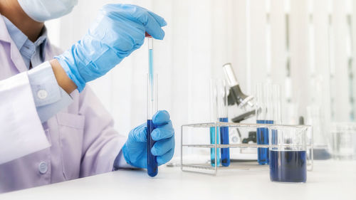 Midsection of scientist examining chemical in laboratory