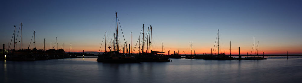 Silhouette sailboats in sea against sky during sunset