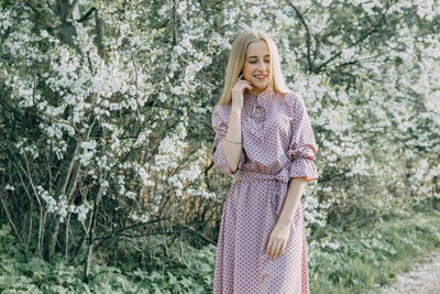 Blonde girl on a spring walk in the garden with cherry blossoms. female portrait, close-up. 