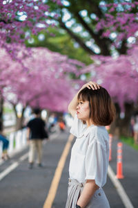 Woman standing by pink flowering tree