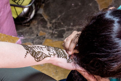 Artist drawing henna tattoo on woman hand