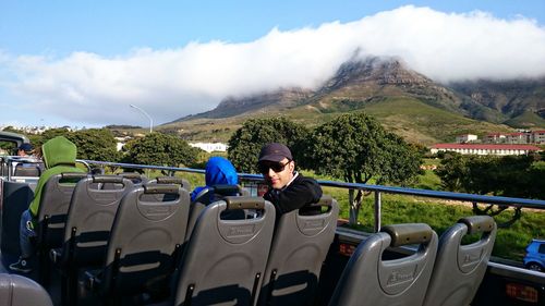 A view of the majestic cloud covered mountains in cape town, young man in the foreground on a bus.