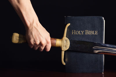 Midsection of man holding paper against black background