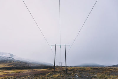 Electricity pylons on land against sky