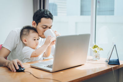 Father and son using smart phone on table