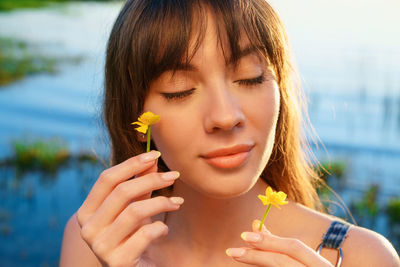 Close-up portrait of a beautiful young woman holding flower