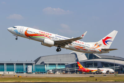 Airplane flying over airport runway against sky