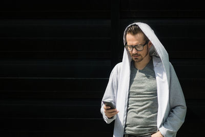 Mid adult man looking away while standing against wall