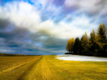 Road amidst field against sky