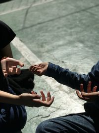 Cropped hands of friends gesturing while sitting on road