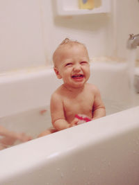 Shirtless baby sitting in bathtub at home