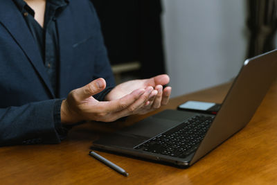 Midsection of businessman using laptop on table