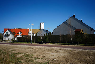 Houses by road against clear blue sky