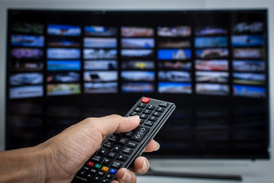 Cropped hand of man holding remote control at home