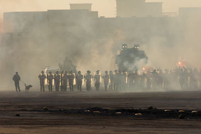 Panoramic view of people in front of factory against sky