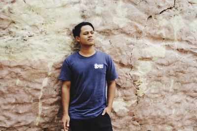 Young man standing against wall