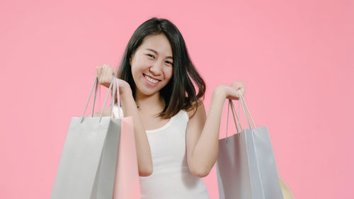 Portrait of a smiling young woman against pink background