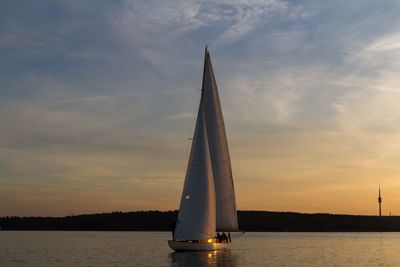 Sailboat sailing in sea at sunset