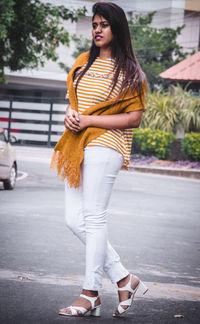 Portrait of young woman standing on road in city