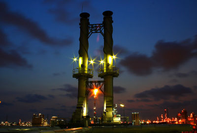 Low angle view of statue against illuminated city at night