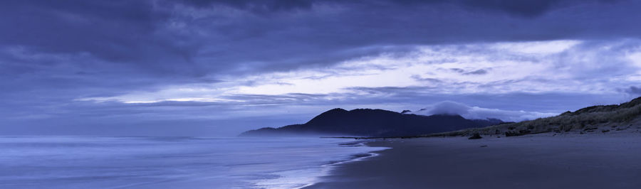 Panoramic view of sea against cloudy sky at sunset