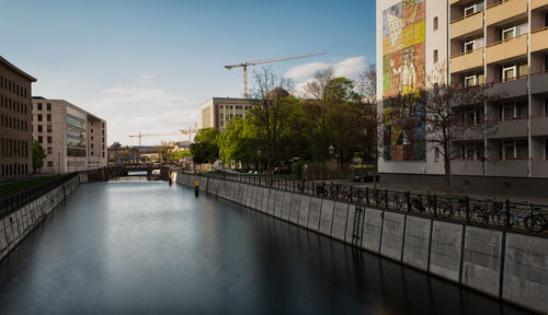 Canal amidst buildings against sky in city