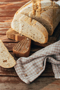 Freshly baked bread loaf on rustic wooden cutting board and napkin