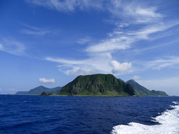 Scenic view of sea and mountains against blue sky
