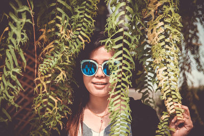 Portrait of smiling young woman against plants