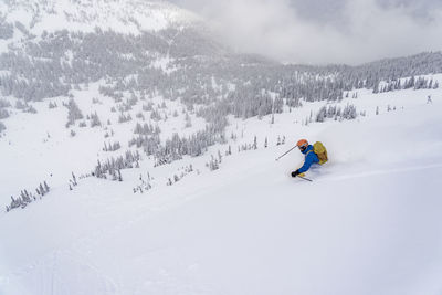 Man skiing on snowy mountain against sky