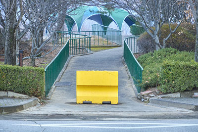 Yellow big sign on footpath by park in city