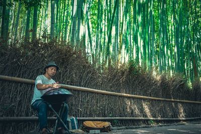 Man sitting on bamboo structure in forest