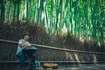 Street musician playing music while sitting against fence