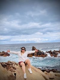 Rear view of woman relaxing on beach against sky